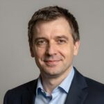 Профессиональный портрет уверенного российского бизнесмена с дружелюбным взглядом на размытом нейтральном фоне