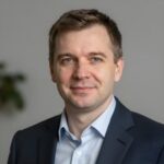 Профессиональный портрет уверенного бизнесмена с дружелюбным взглядом на нейтральном размытом фоне студии